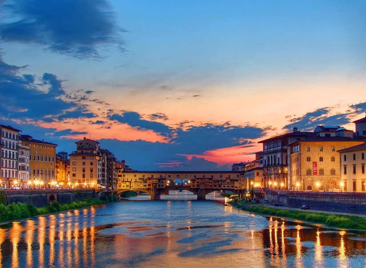 The historic Ponte Vecchio bridge in Florence bathed in warm sunset light — an iconic scene among must-visit places in Italy Ponte Vecchio bridge at sunset with gold jewelry shops reflected in the Arno River