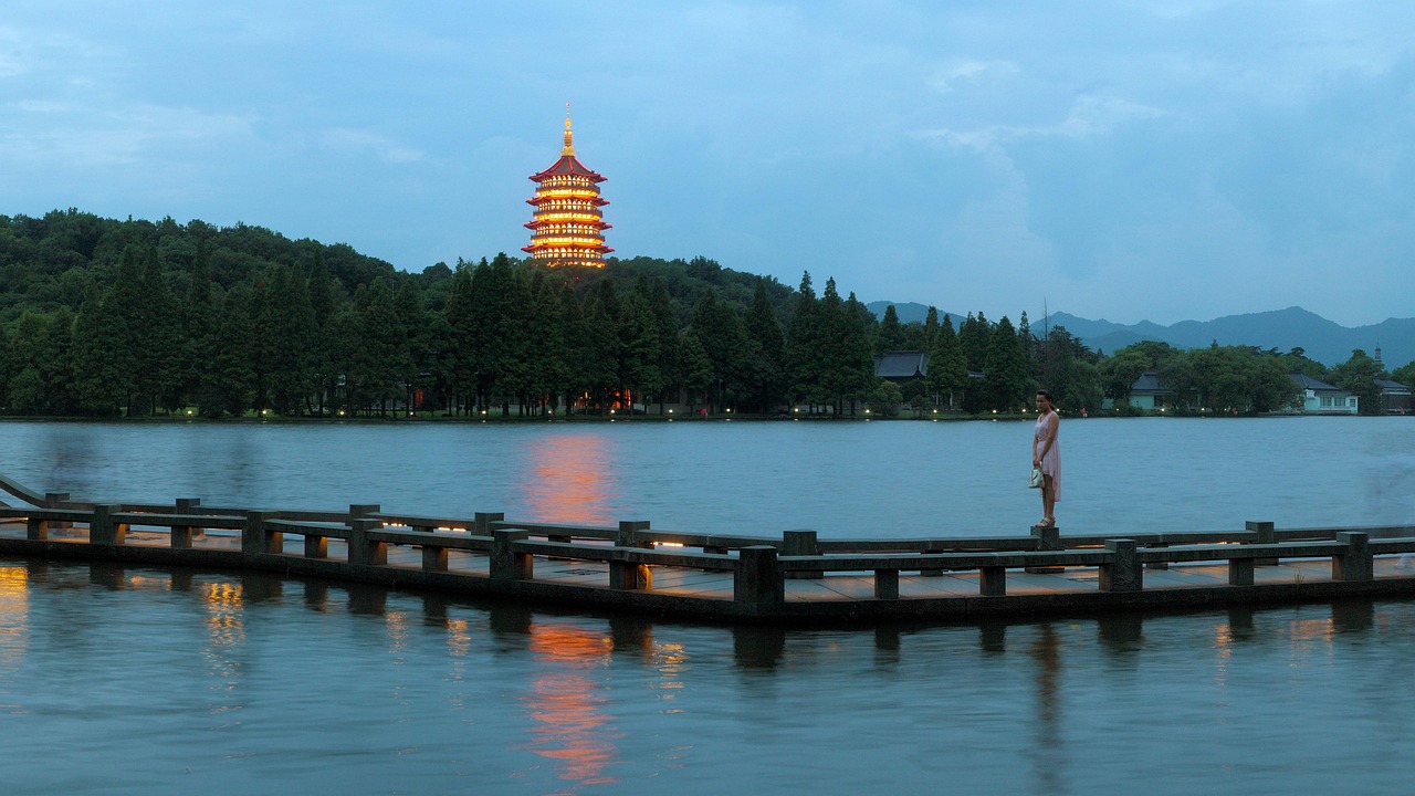 Misty morning on Hangzhou’s West Lake reveals the iconic Broken Bridge arching over calm water, framed by weeping willows and a distant pagoda Serene West Lake in Hangzhou with Broken Bridge, willow trees, and misty pagoda in background