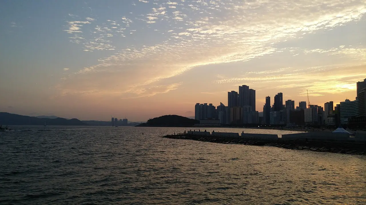 Stunning sunset view over Haeundae Beach in Busan — a vibrant, cosmopolitan coastal gem among the top places in Korea Haeundae Beach at sunset with palm trees, surfers, and high-rise buildings in background