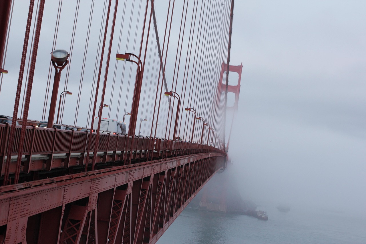 The iconic red suspension bridge emerges from coastal mist — a timeless symbol among must-visit places in the USA Golden Gate Bridge arching over misty blue water with sailboats below