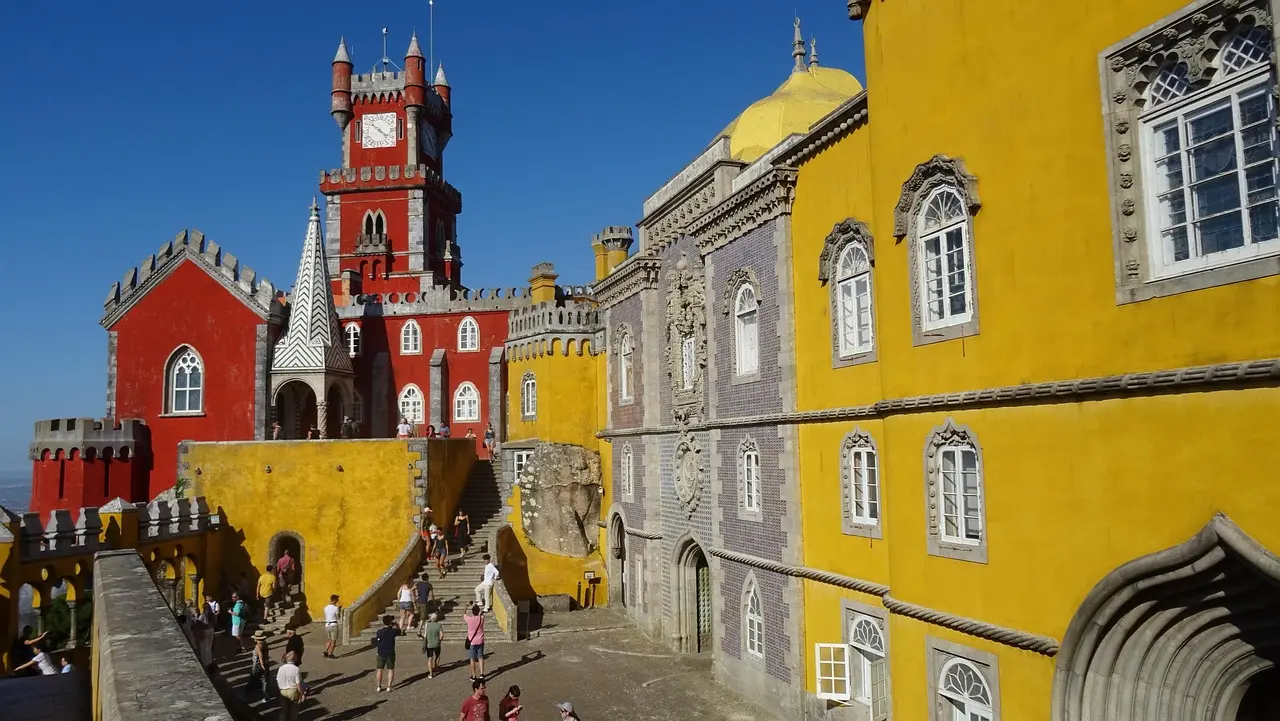 The whimsical, multicolored Pena Palace perched atop the Sintra Mountains, surrounded by dense Atlantic forest Pena Palace in Sintra with vivid yellow and red towers rising above lush green hills