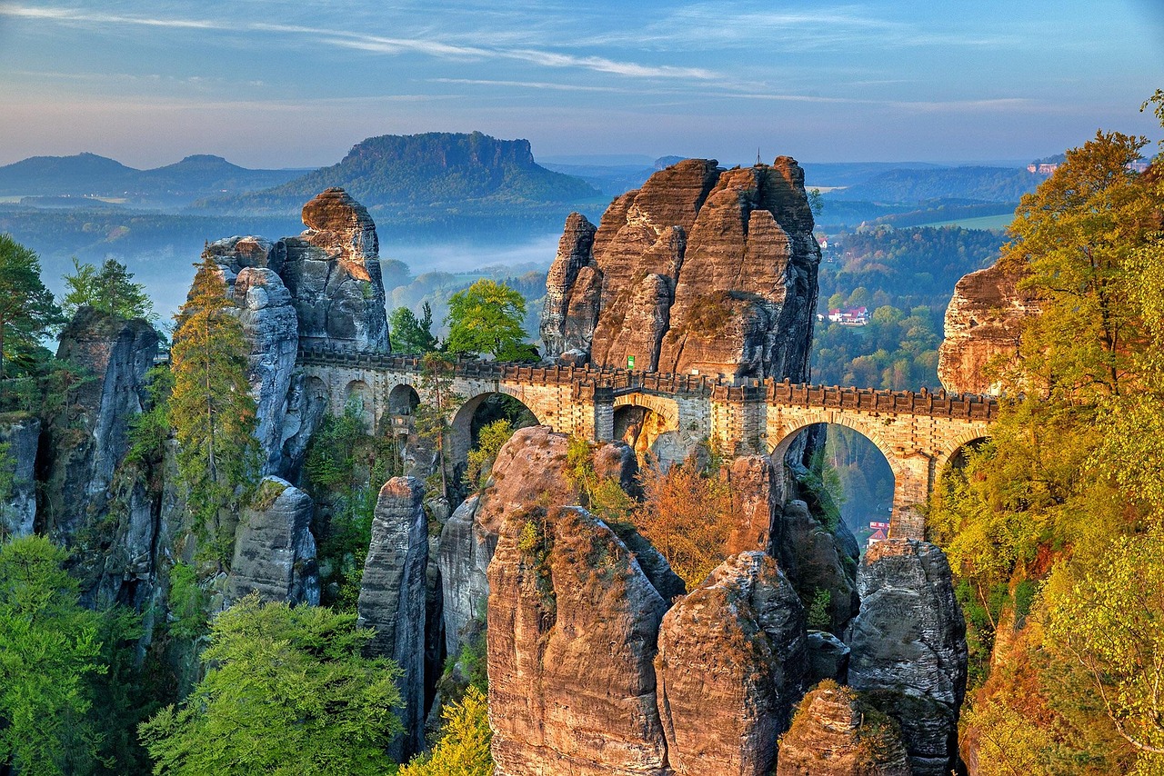 The iconic Bastei Bridge arcing across jagged sandstone cliffs above the Elbe River — a thrilling natural landmark among the 15 must-visit places in Germany. Bastei Bridge stretching across dramatic sandstone cliffs above the Elbe River