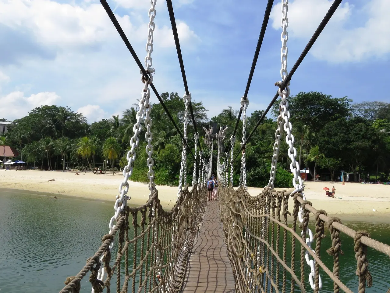 Serene Palawan Beach on Sentosa Island—a top in Singapore must-visit coastal escape offering soft sands, crystal-clear waters, and panoramic views of the mainland skyline. Sentosa Island beach with palm trees, turquoise water, and distant skyline