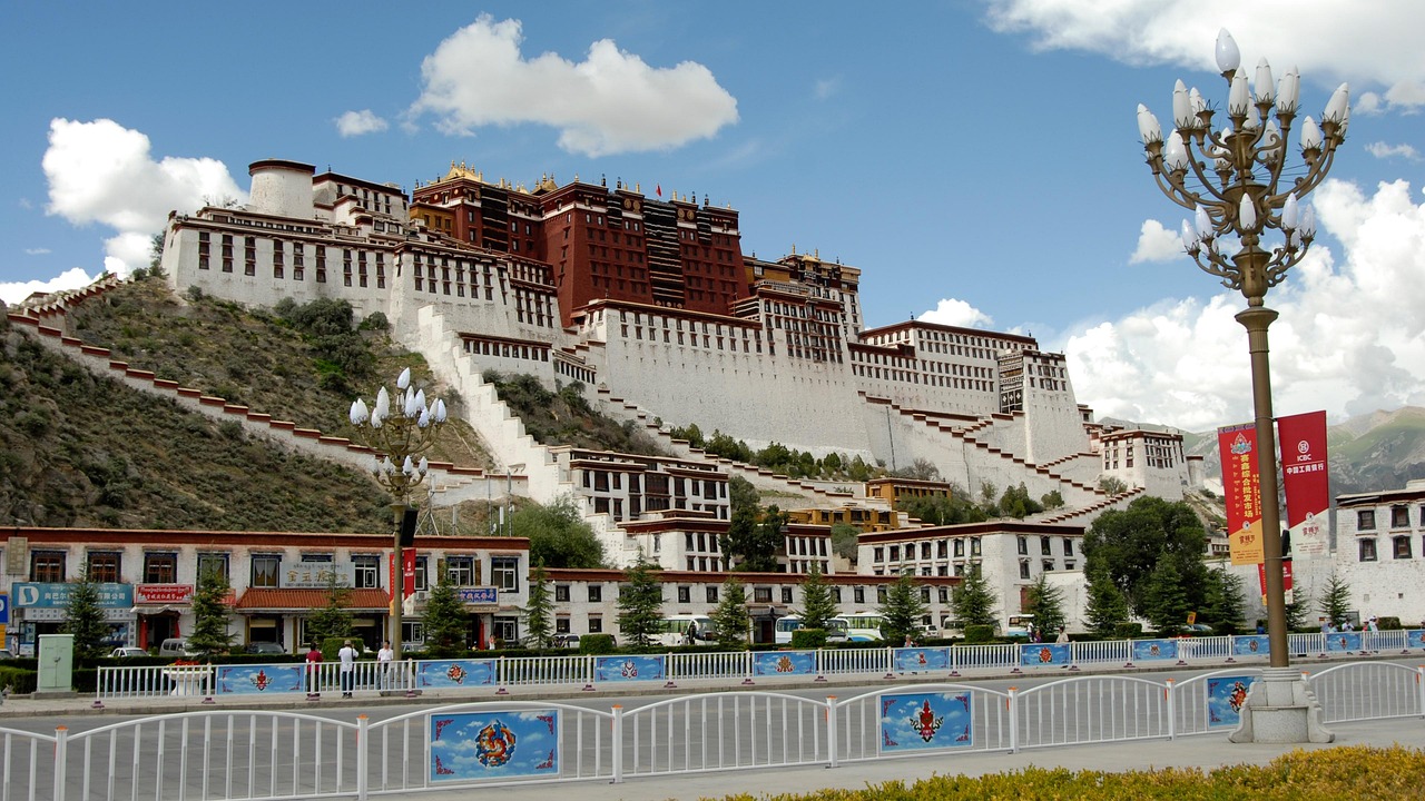 The imposing white-and-red Potala Palace dominates the Lhasa skyline, set against crisp blue skies and snow-dusted Himalayan foothills Potala Palace rising majestically above Lhasa city against a vivid blue Himalayan sky