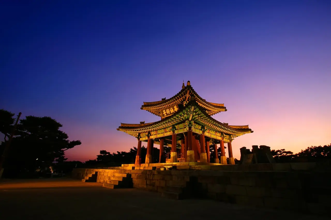Golden-hour view of Hwaseong Fortress in Suwon — a harmonious blend of history, architecture, and philosophy among Korea’s top places in Korea Sunset view of Hwaseong Fortress walls and Paldalmun Gate in Suwon
