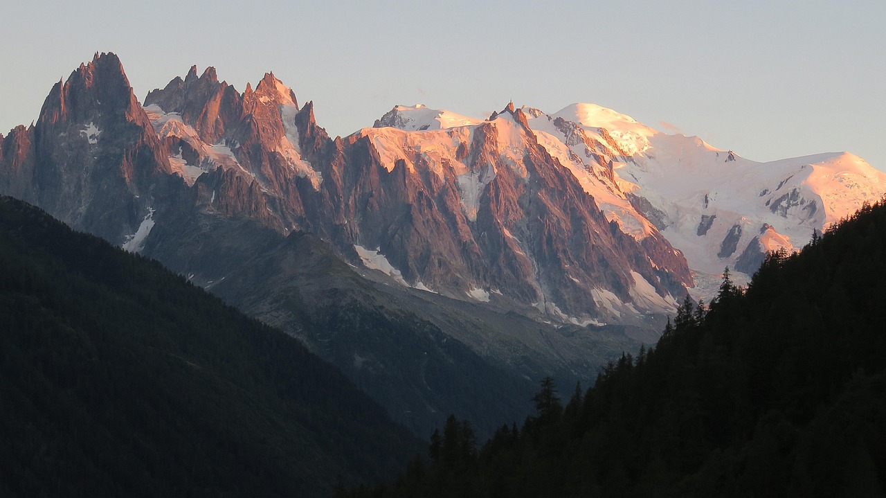 Majestic snow-covered Mont Blanc towering above the Chamonix valley, with the Aiguille du Midi cable car station in foreground Snow-capped Mont Blanc viewed from Chamonix valley with cable car station