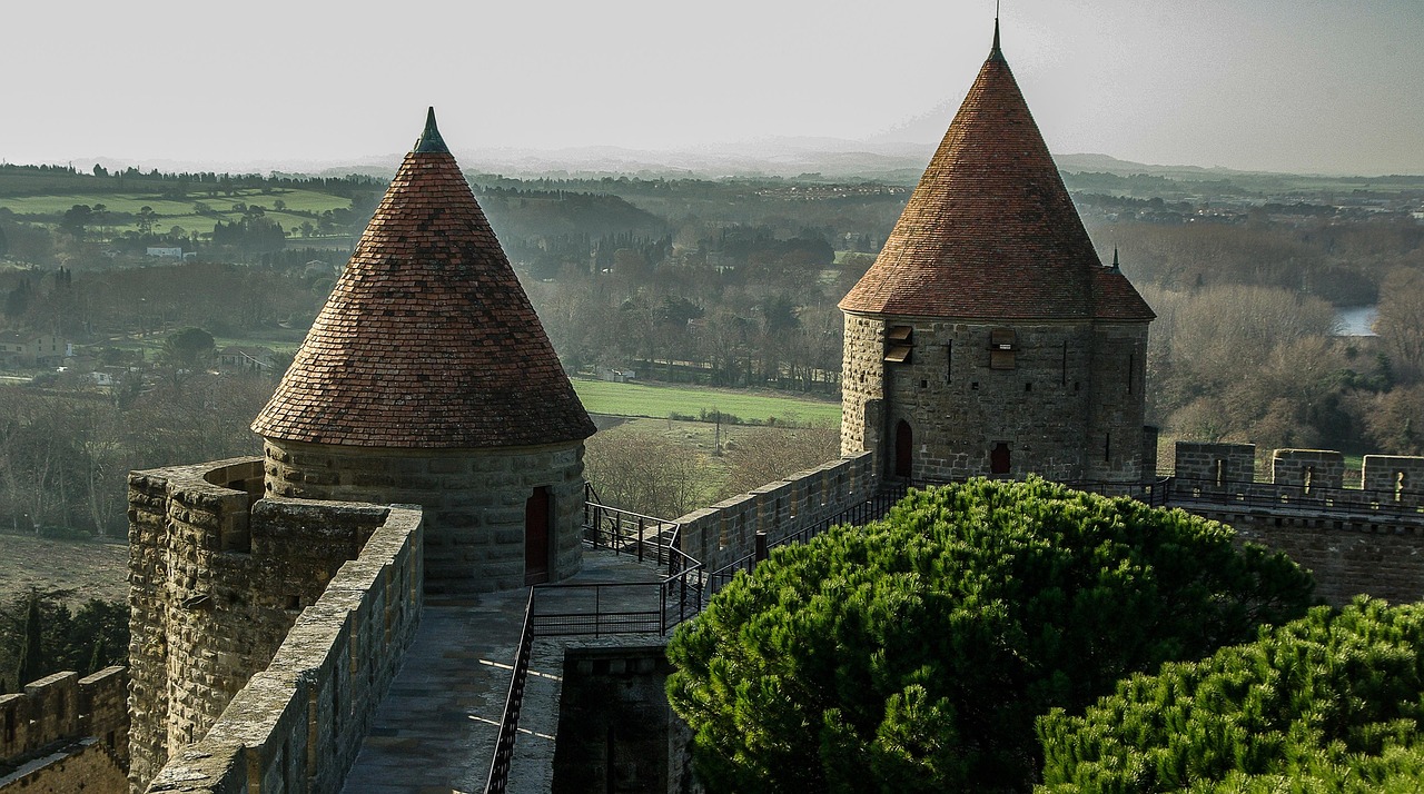 Warm sunset light illuminating Carcassonne’s ancient fortified walls and conical stone towers in southern France Sunset view of Carcassonne’s fortified walls and Gothic towers