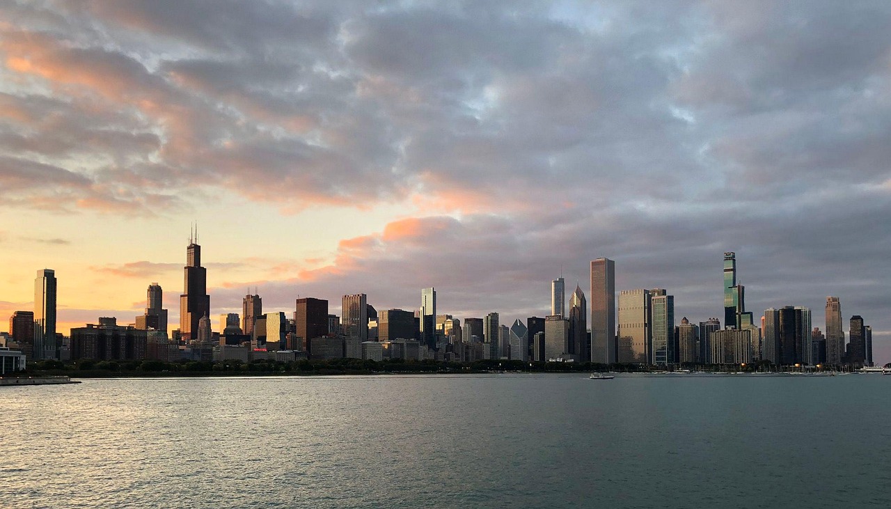 Steel-and-glass towers mirrored in golden lake waters — an elegant, urban moment among must-visit places in the USA Modern Chicago skyline reflected in calm waters of Lake Michigan at sunset