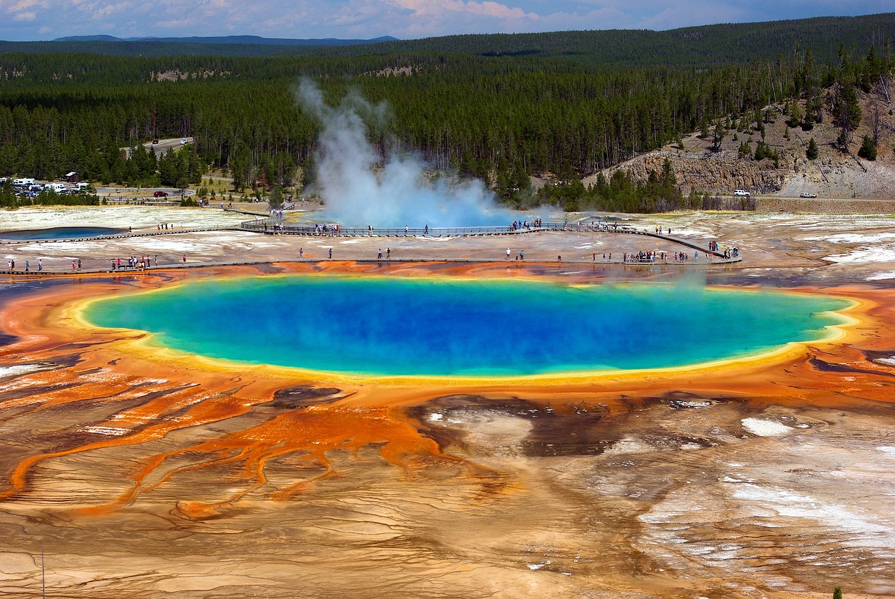 The otherworldly colors and steaming edges of Grand Prismatic Spring — a highlight among must-visit places in the USA Vibrant turquoise and orange Grand Prismatic Spring surrounded by steam and pine forest
