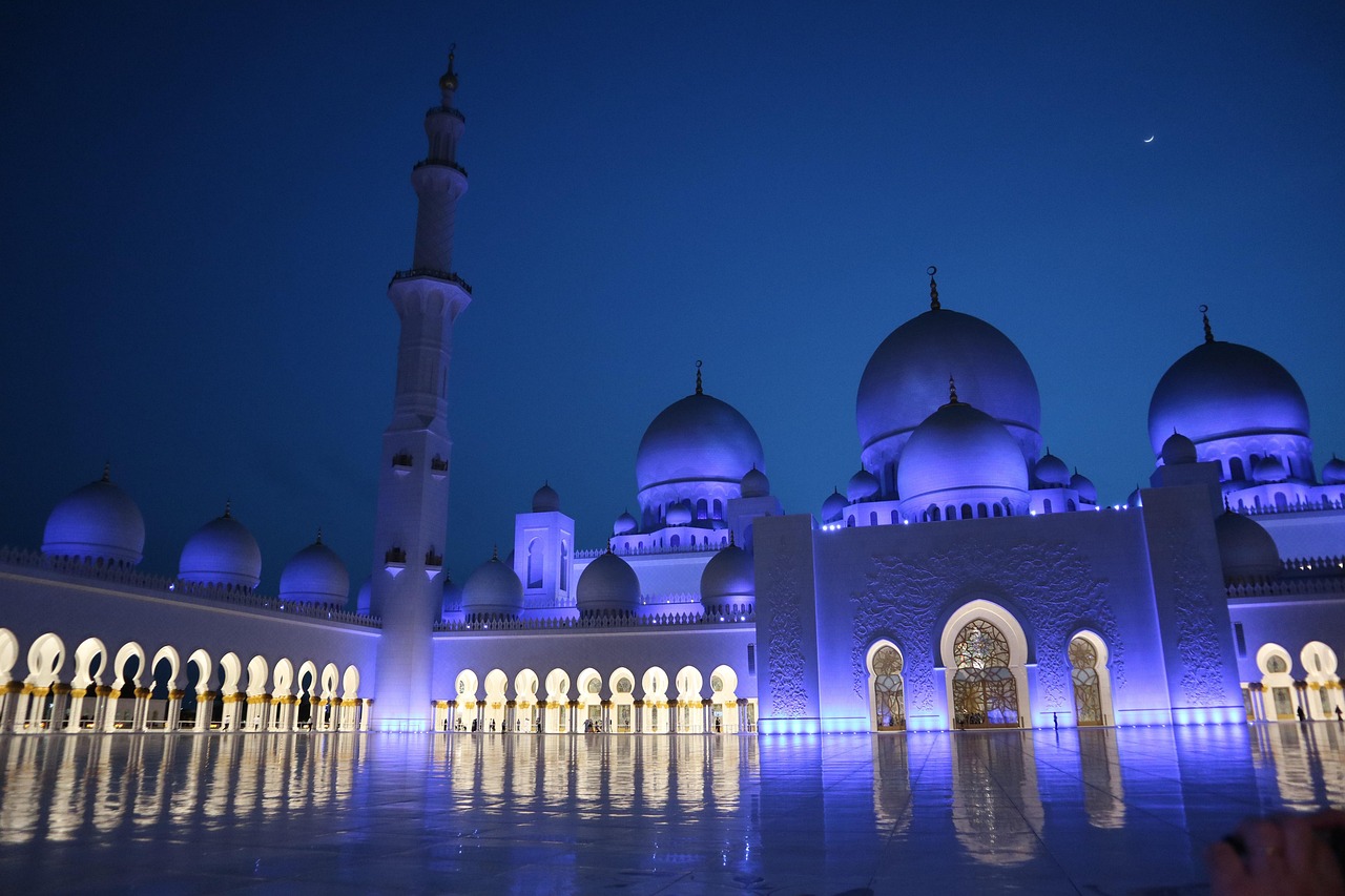 Wide-angle view of the serene central courtyard of Sheikh Zayed Grand Mosque featuring symmetrical fountains and ornate blue-domed architecture Symmetrical marble courtyard of Sheikh Zayed Grand Mosque with blue domes and fountains