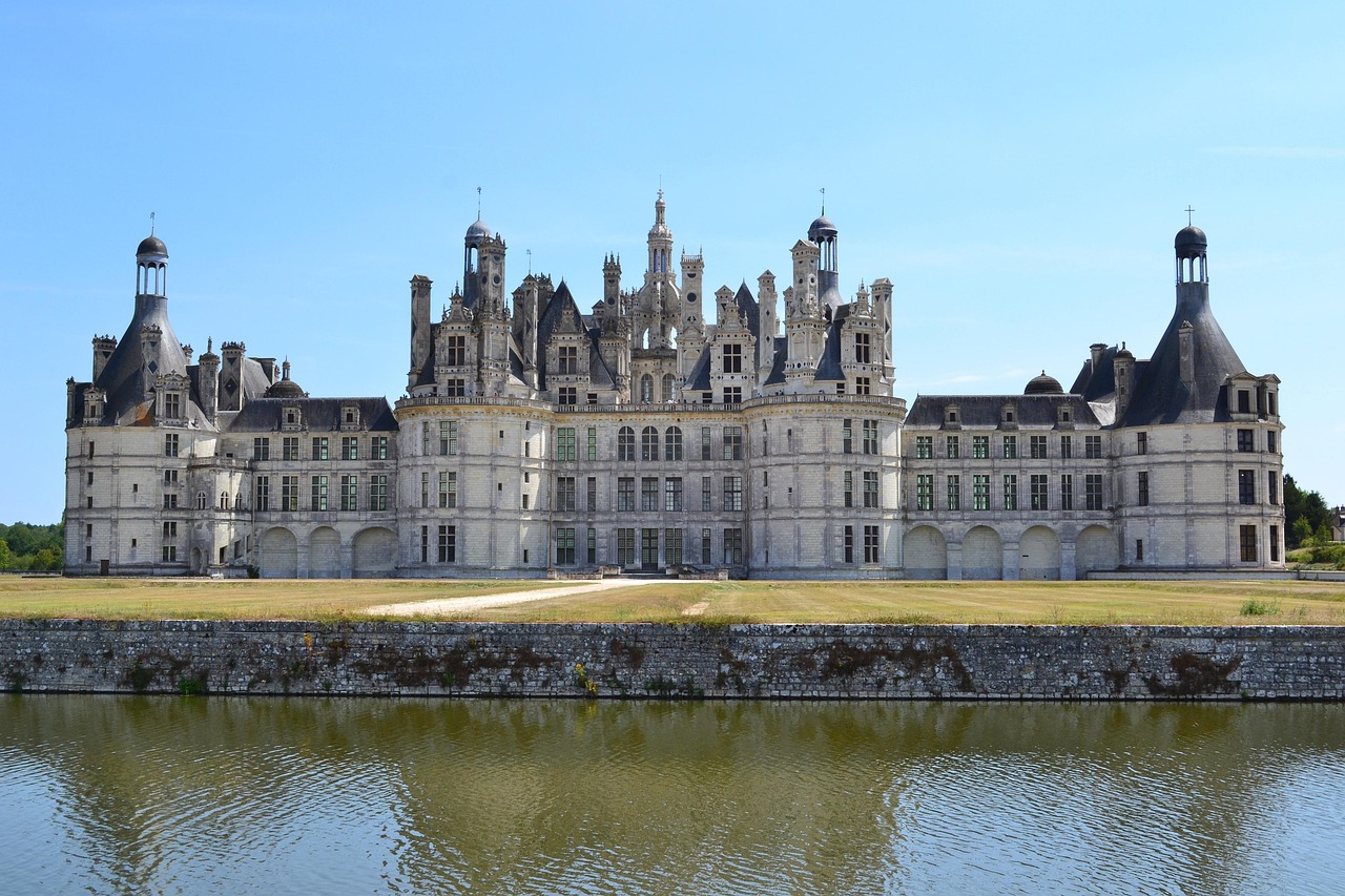Château de Chambord mirrored perfectly in a tranquil pond, framed by golden autumn trees — a quintessential Loire Valley scene Château de Chambord reflected in still water with autumn foliage