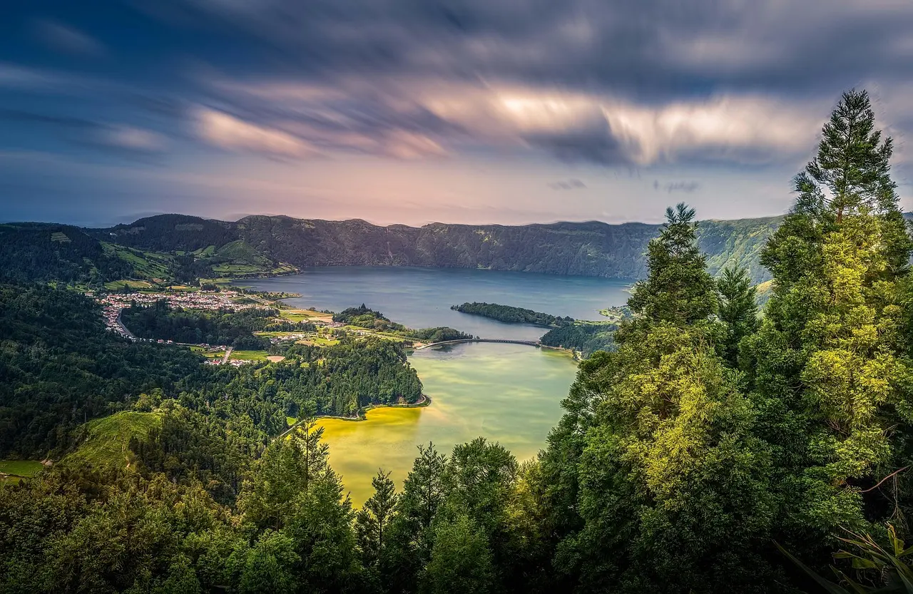 Drone perspective of the iconic twin lakes of Sete Cidades in the Azores — vivid blue and emerald green nestled within a collapsed volcanic caldera Aerial view of Lagoa das Sete Cidades showing contrasting blue and green volcanic lakes surrounded by lush hills