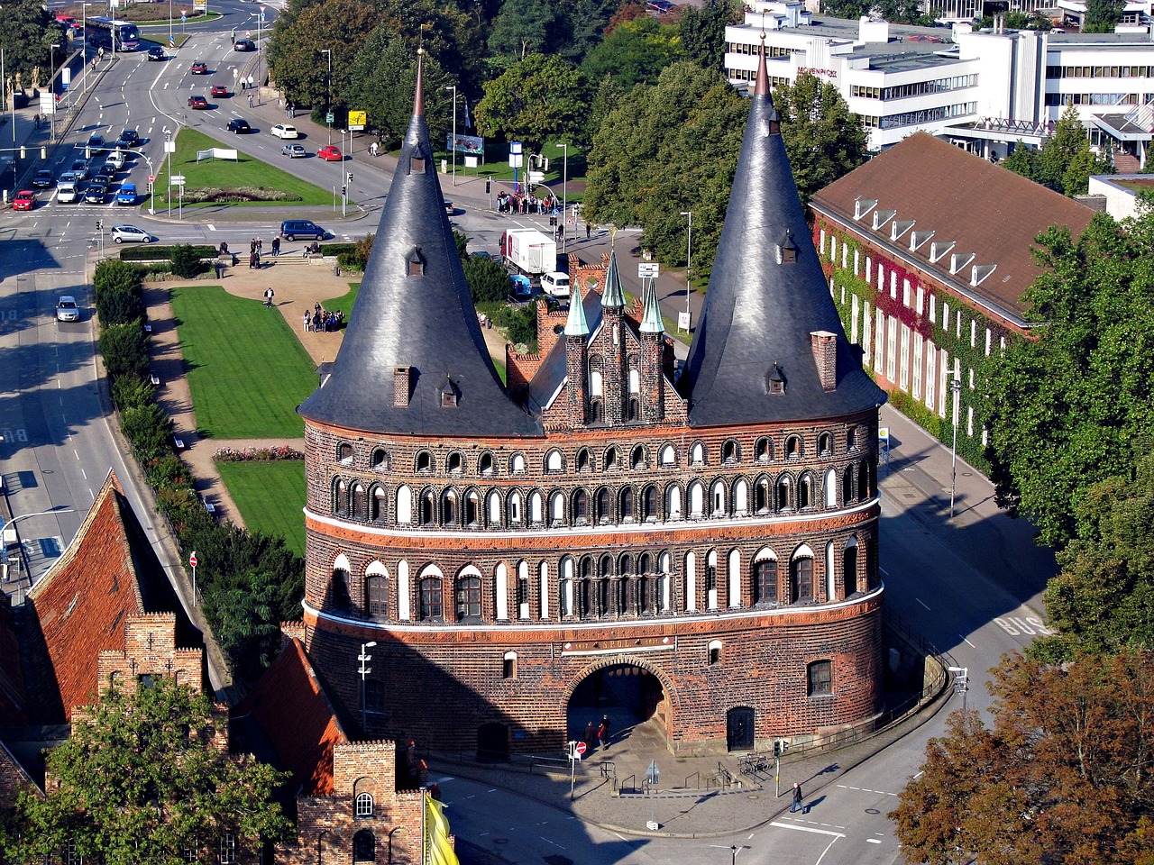 The Holstentor gate in Lübeck at first light — its twin brick towers framing a quiet cobblestone street — a serene, historic anchor among the 15 must-visit places in Germany. Holstentor gate in Lübeck with brick towers and cobblestone street at dawn