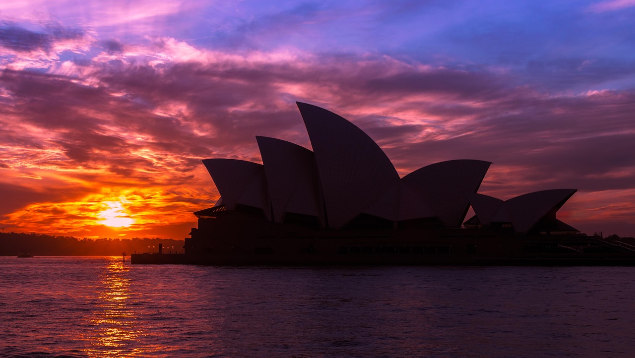 The iconic Sydney Opera House bathed in warm evening light, framed by the Harbour Bridge and calm waters — a quintessential Australian landmark Sydney Opera House at golden hour with harbour bridge and water reflections