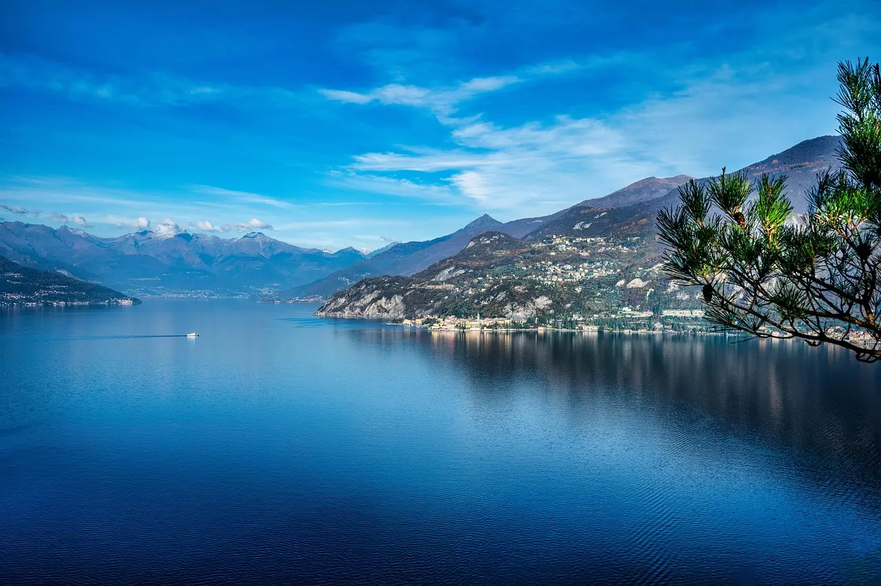 Charming Bellagio on Lake Como — pastel buildings, mountain reflections, and tranquil waters define this elegant lakeside gem among must-visit places in Italy Bellagio village on Lake Como with pastel buildings, cypress trees, and calm azure water reflecting mountains