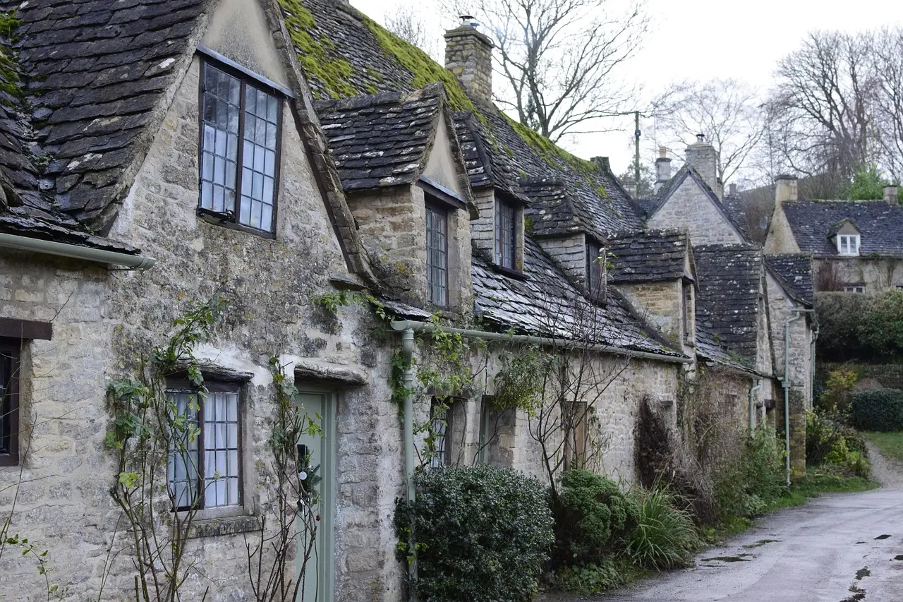 Encantador pueblo en los Cotswolds con casas de piedra caliza y jardines floridos Pueblo típico de los Cotswolds con casas de piedra dorada y flores