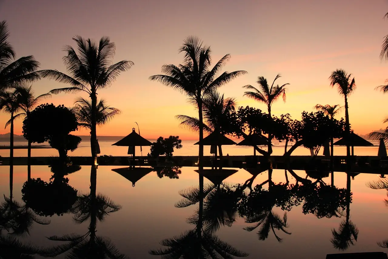 Romantic black-sand beach walk at sunset in Bali — capturing the emotional intimacy that defines top honeymoon destinations in Asia Couple holding hands walking barefoot along a quiet black-sand beach at sunset in Bali, silhouetted against golden sky
