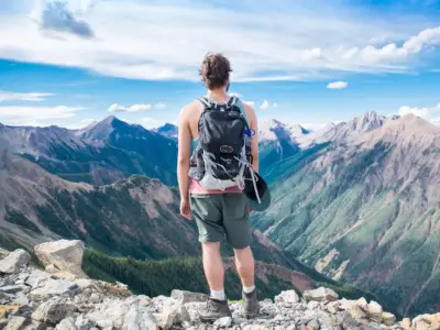 Aventurero con mochila mirando paisaje montañoso al amanecer