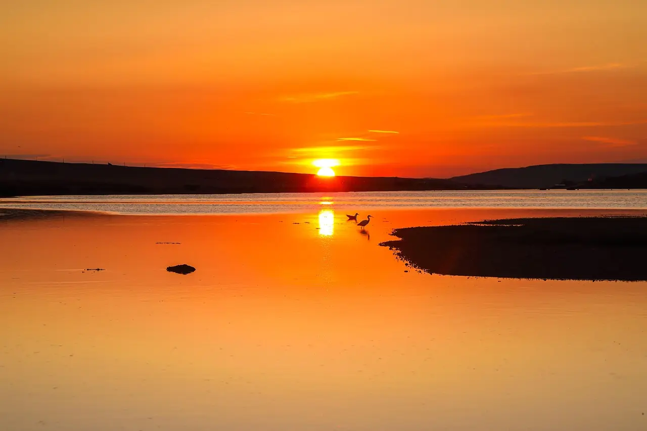 Dramatic coastal scenery in Krabi — highlighting why this region is among the most photogenic and experiential honeymoon destinations in Asia Sunset view from a limestone cliff overlooking emerald-green lagoon and small wooden longtail boat in Krabi, Thailand
