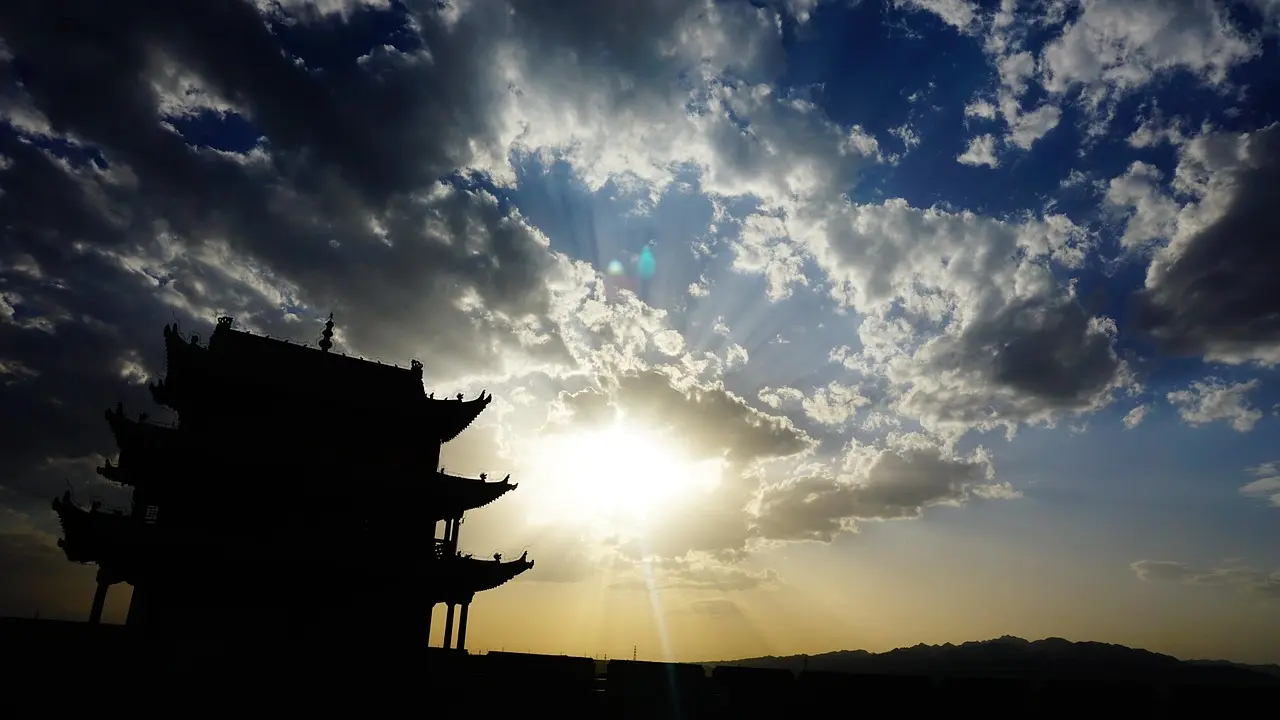 A lone traveler watches dawn break over the winding ramparts of the Great Wall — a powerful symbol of why visiting ancient landmarks inspires wonder and reflection. Silhouette of a traveler gazing at sunrise over the Great Wall of China