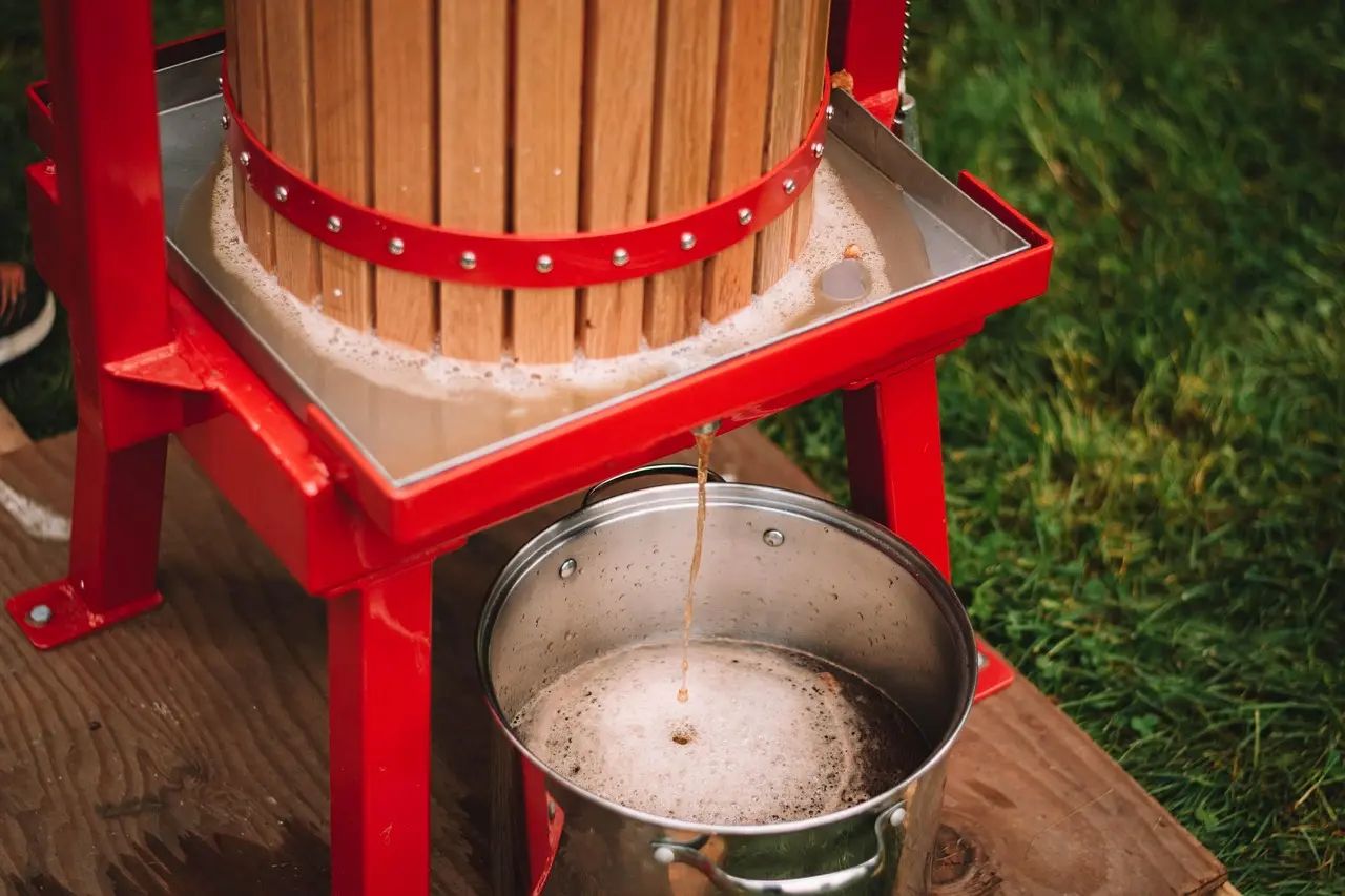 Normandy’s cider-making tradition epitomizes food travel focused on origin — where apple variety, soil, and pressing method collectively define flavor. Traditional wooden cider press in Normandy orchard with baskets of russet and golden apples