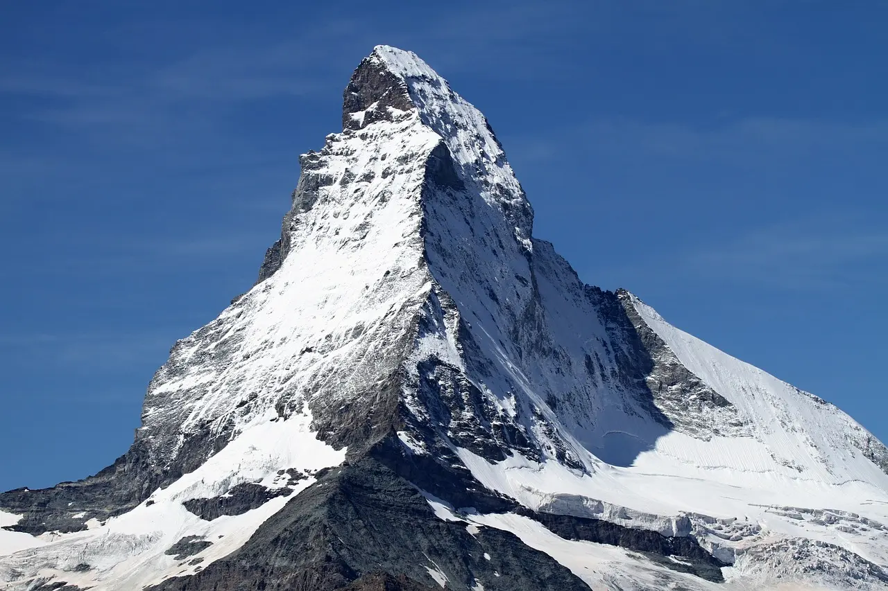Alpinista escalando una montaña rocosa con nieve