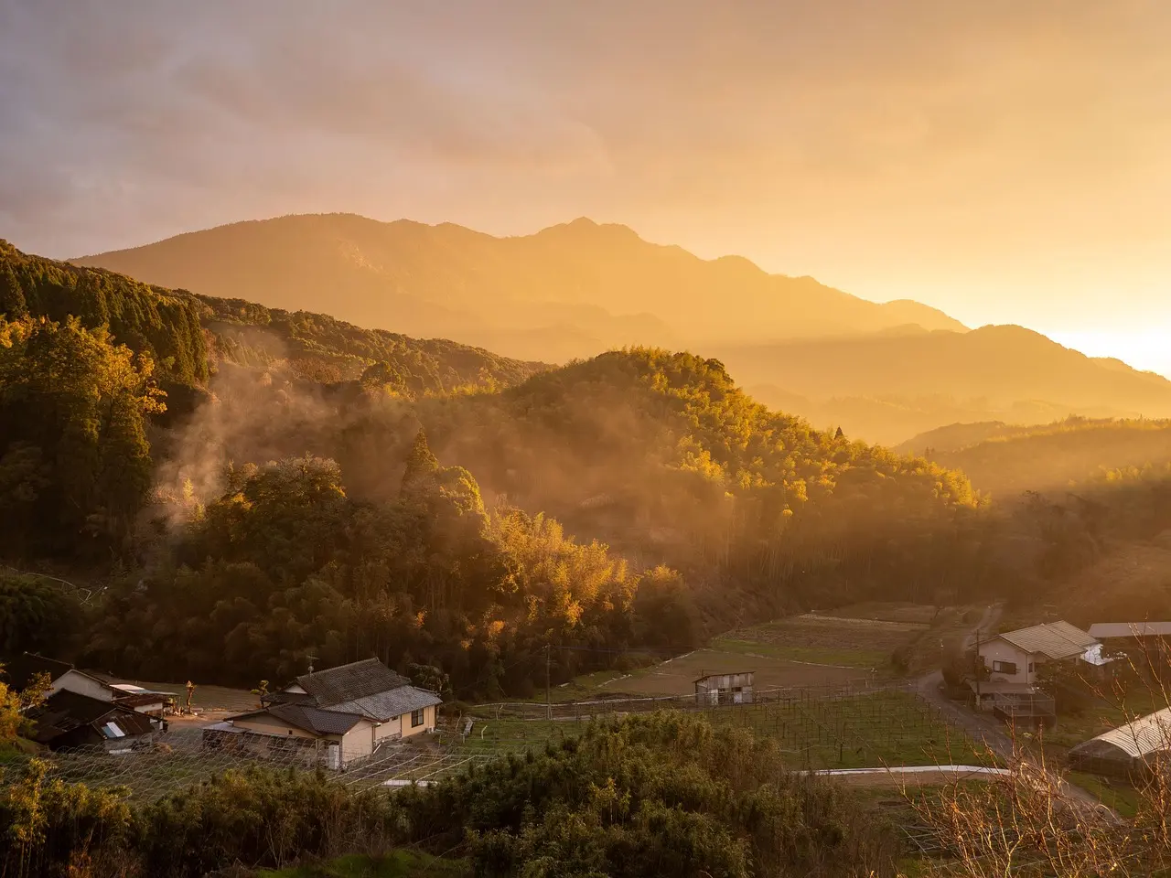 A serene moment of mindful breathing in a mountain retreat—symbolizing the core purpose of relaxation travel: intentional stillness amid natural grandeur. A person sitting peacefully on a wooden deck overlooking misty mountains at dawn, eyes closed, breathing deeply