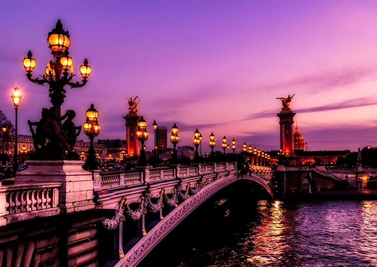 Evening romance by the Seine in Paris — a classic European honeymoon destination Eiffel Tower illuminated at night with couples embracing on the Seine riverbank promenade