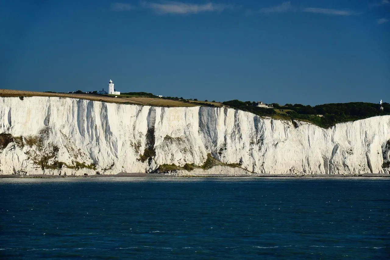 Los famosos acantilados blancos de Dover brillando bajo el sol junto al Canal de la Mancha Acantilados blancos de Dover con el mar azul al fondo