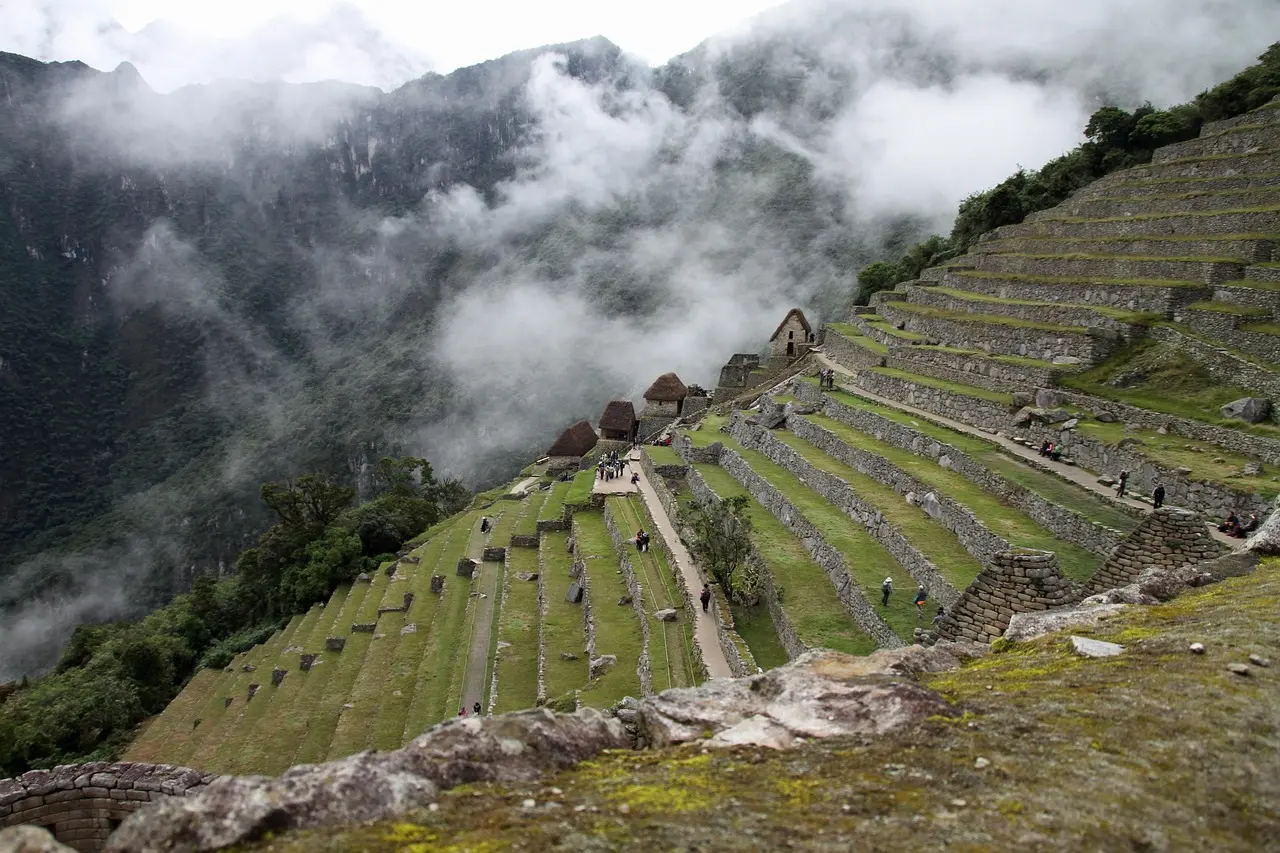 Sunrise view from the Inca Trail with mist rising over the Urubamba Valley toward Machu Picchu Hiker standing on Inca Trail stone path overlooking misty Andean valley and distant Machu Picchu ruins