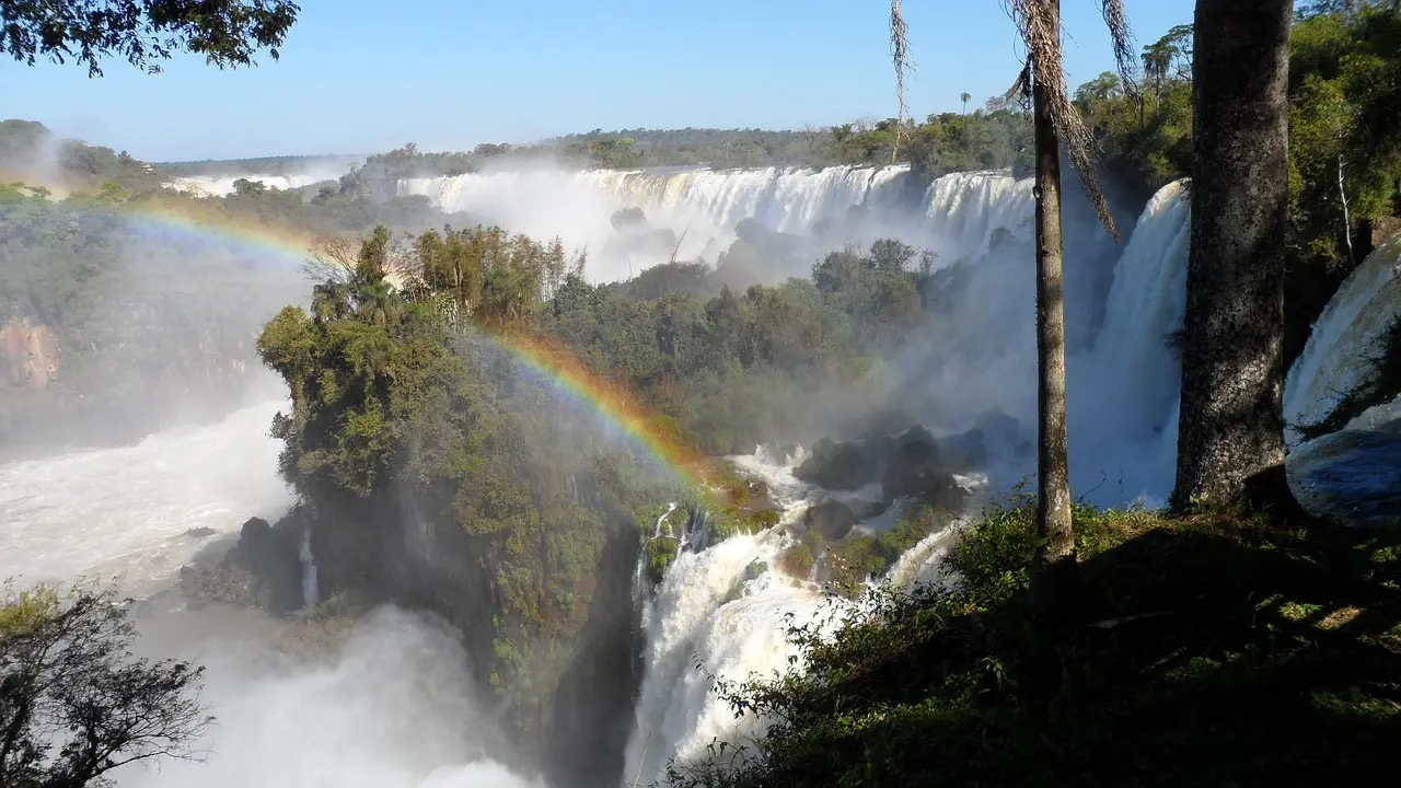 Las majestuosas Cataratas del Iguazú en Brasil, con un arcoíris formándose en la neblina bajo el sol tropical Cataratas del Iguazú con arcoíris bajo el sol brillante