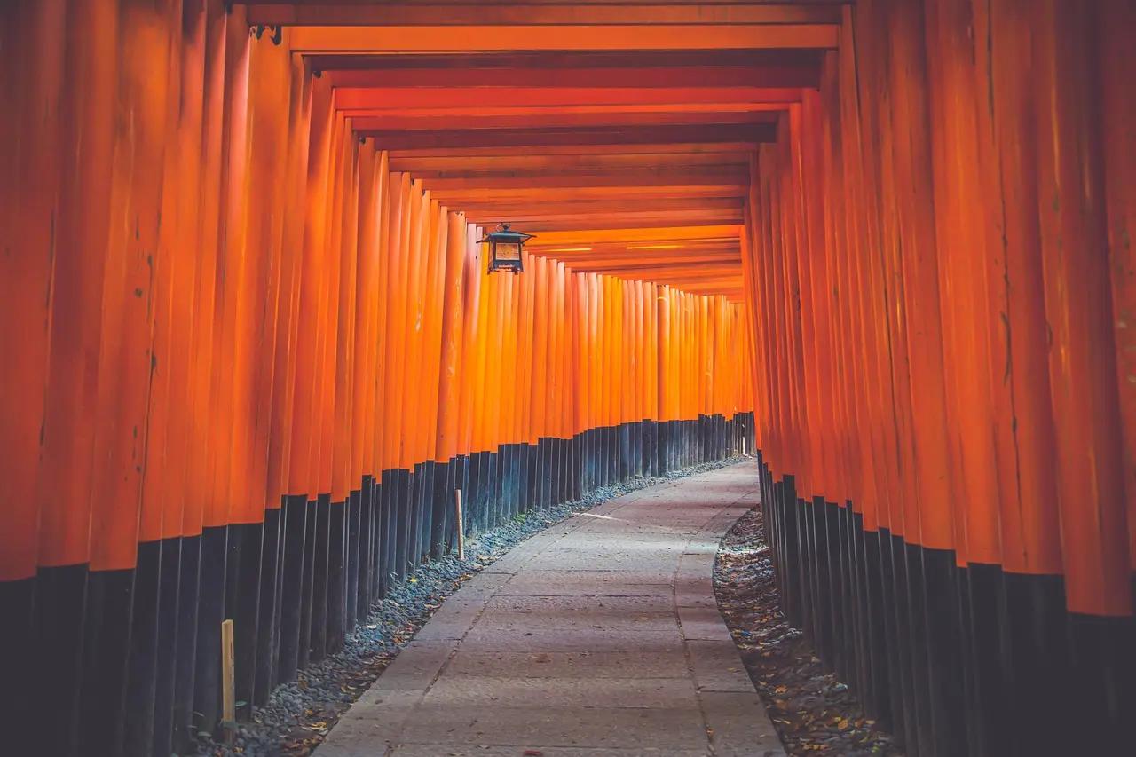 A serene, atmospheric shot of Fushimi Inari Shrine’s winding torii path — a deeply symbolic and visually mesmerizing landmark within Japan’s top travel destinations for landmark photography Long corridor of red torii gates at Fushimi Inari Shrine in Kyoto, with soft morning light and mist
