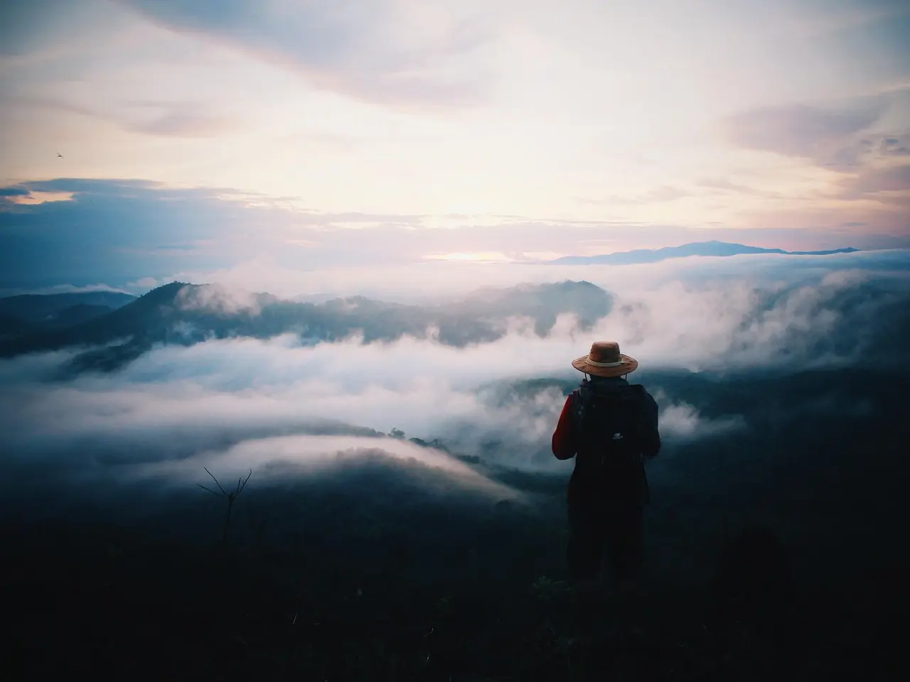 Viajero contemplando amanecer en cima de montaña