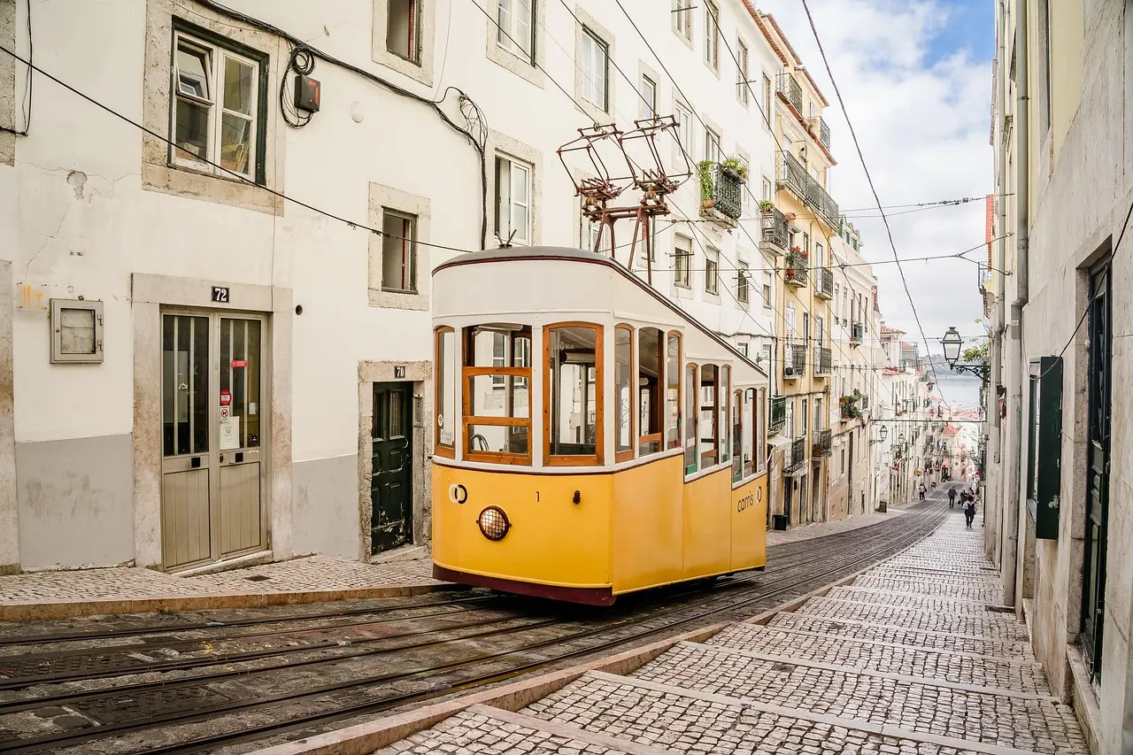 Tranvía amarillo subiendo una colina en Lisboa con azulejos
