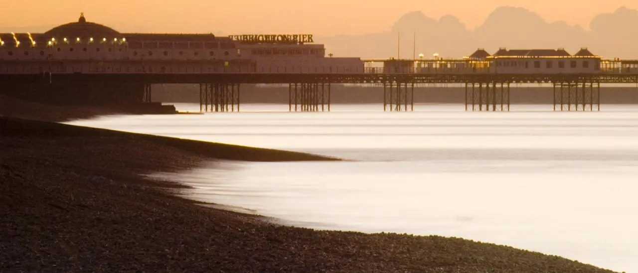 El icónico muelle de Brighton iluminado durante el atardecer en la costa sur de Inglaterra Muelle de Brighton al atardecer con luces encendidas