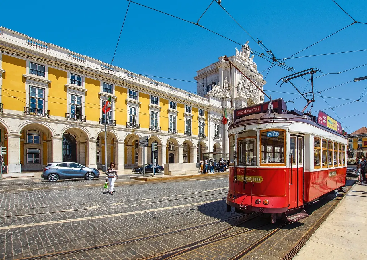 Charming tram ride through historic Alfama in Lisbon — a vibrant, affordable European honeymoon destination Tram 28 winding through narrow cobbled streets of Lisbon’s Alfama district with orange rooftops and church spires