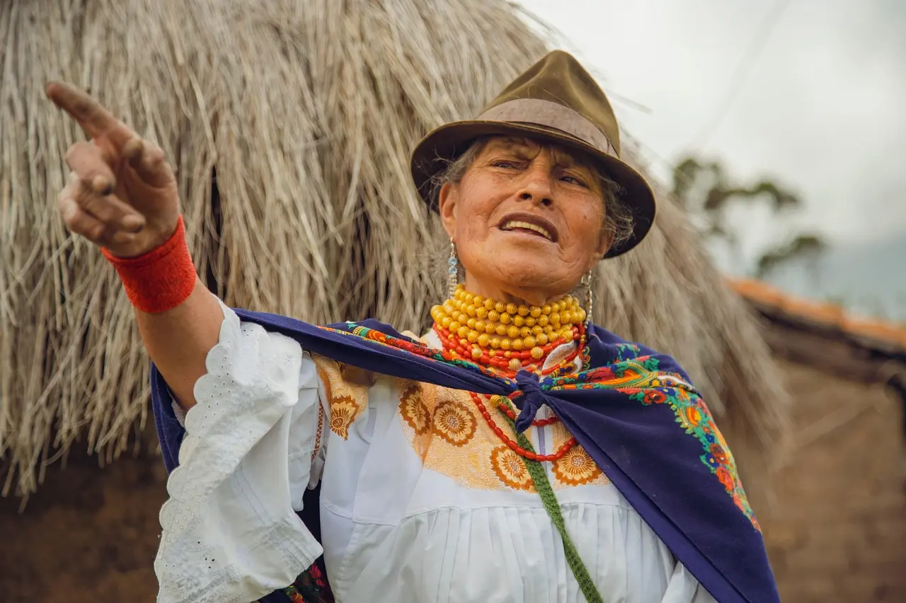 True food travel in Oaxaca means participating in ancestral maize preparation — honoring biodiversity, tradition, and the living connection between people and place. Indigenous woman grinding blue maize on traditional stone metate in Oaxacan village courtyard
