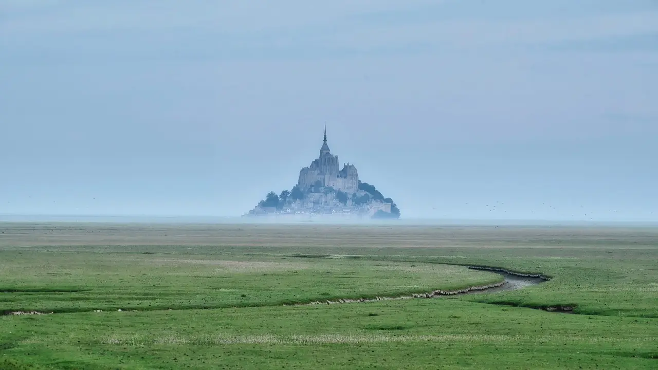 Mont Saint-Michel al amanecer, rodeado por las aguas de la bahía normanda Mont Saint-Michel rodeado de agua al amanecer