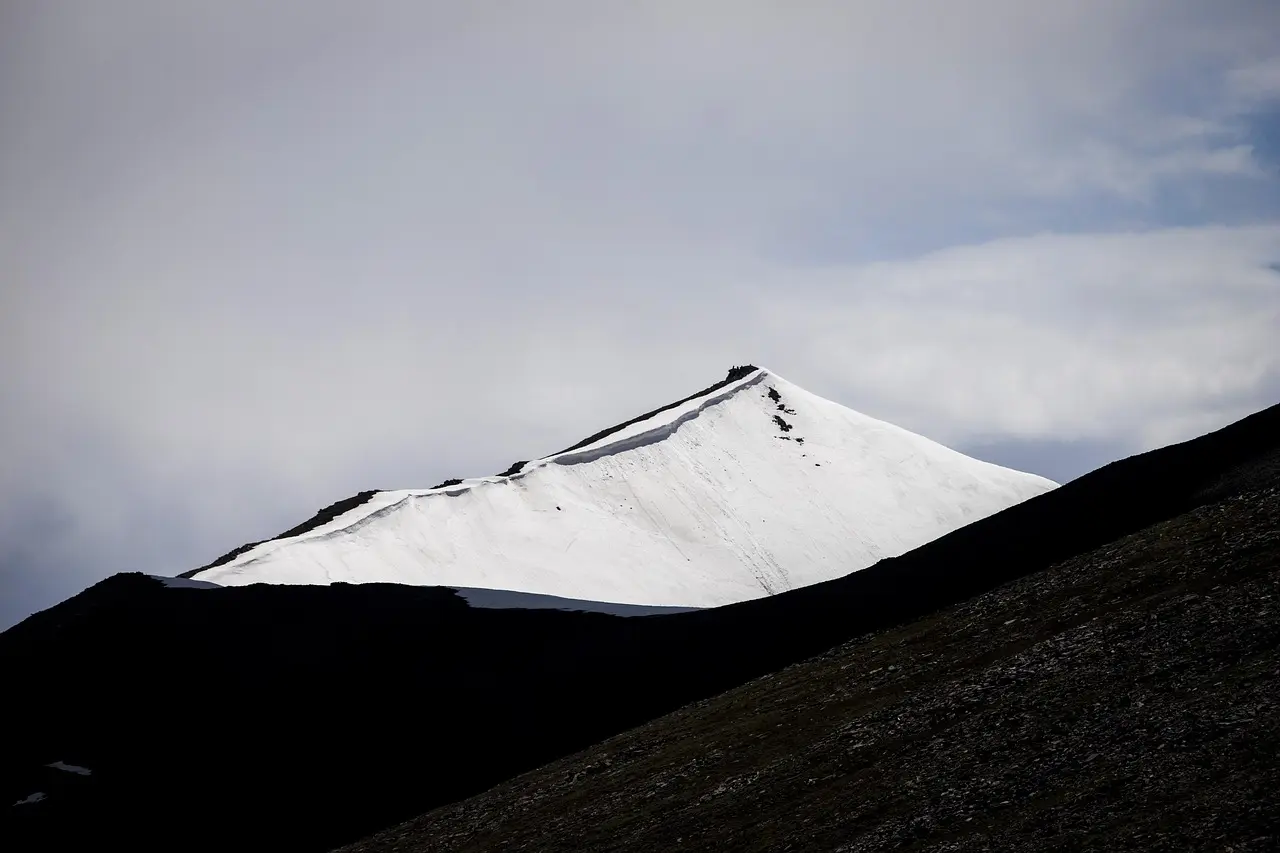 Food travel in the Peruvian Andes celebrates biodiversity — each vibrant potato variety reflects centuries of adaptation to extreme altitude and microclimates. Quechua farmer holding multicolored native potatoes on high-altitude Andean field with snow-capped peaks