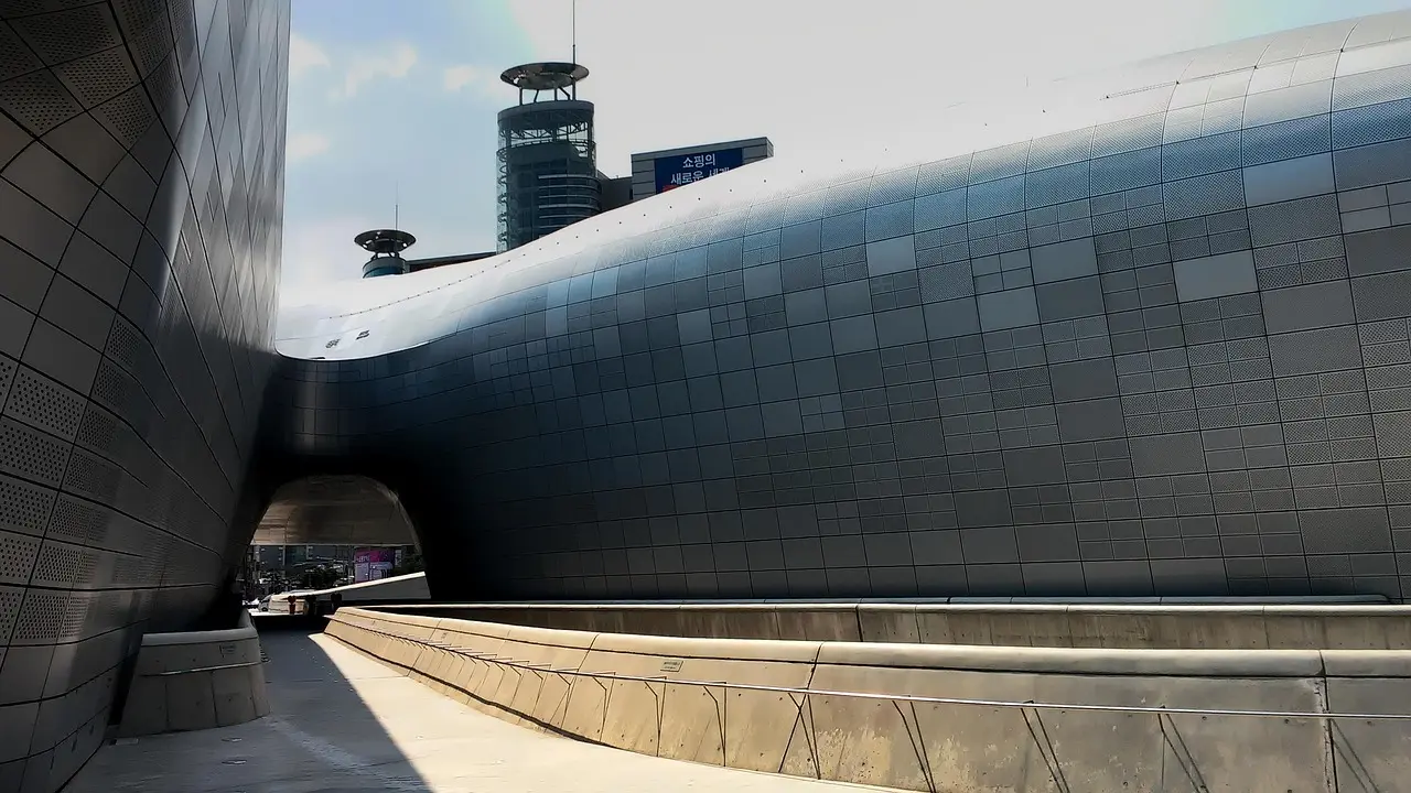 Dongdaemun Design Plaza at night: A landmark fusion of innovation and tradition in Seoul’s top-tier shopping destination for travelers Futuristic silver architecture of Dongdaemun Design Plaza at dusk with illuminated signage and crowds entering