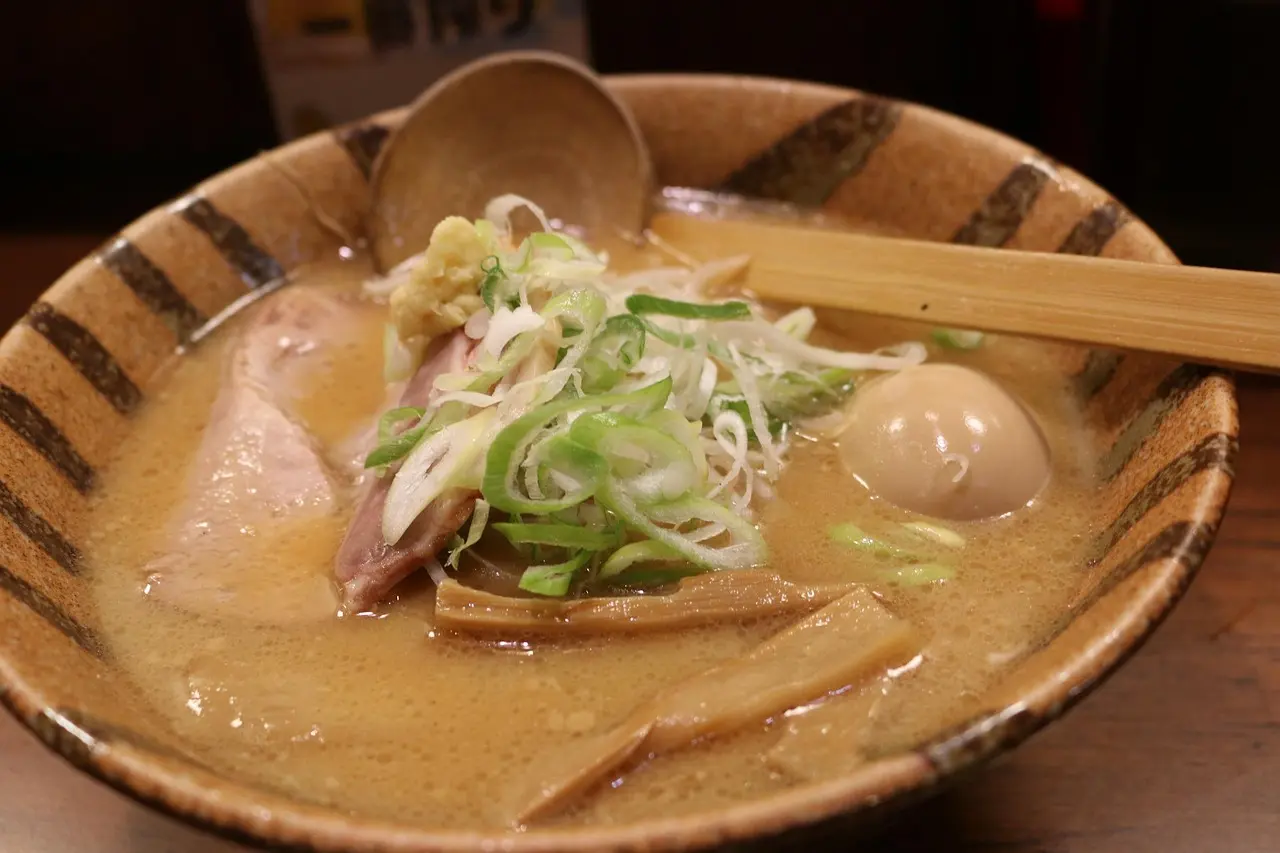 Hands-on miso fermentation workshop in a historic Kyoto machiya—part of Japan's living culinary heritage A smiling woman in Kyoto wearing a blue apron, shaping miso paste with her hands beside ceramic bowls and bamboo tools