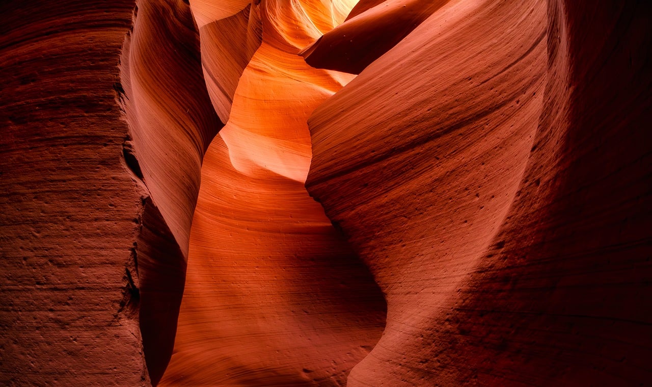Sunlight beams down into the narrow passageway of Antelope Canyon, highlighting the rippling textures of the orange-red rock walls Sunlight streaming through the narrow opening of Antelope Canyon, illuminating curved sandstone walls