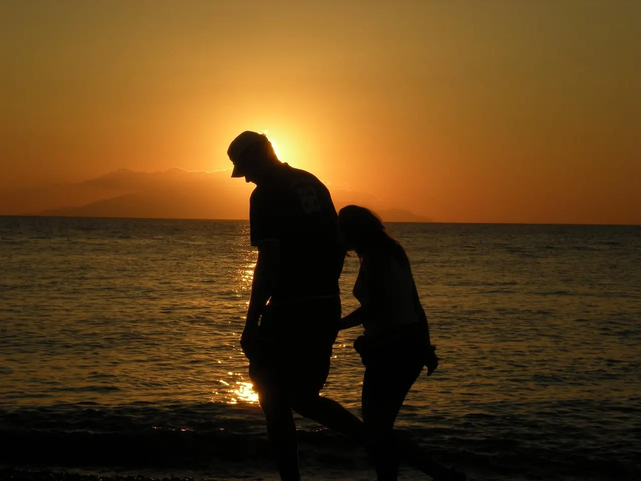 Iconic Santorini caldera view at sunset — one of the most beloved honeymoon destinations in Europe Aerial view of Santorini's white-washed buildings cascading down volcanic cliffs toward the Aegean Sea at golden hour