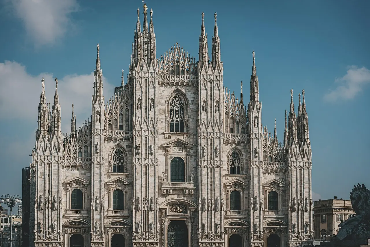 La impresionante fachada gótica del Duomo de Milán, con sus agujas y estatuas, representa la mezcla de historia y modernidad entre los lugares que ver en Italia. Fachada detallada del Duomo de Milán