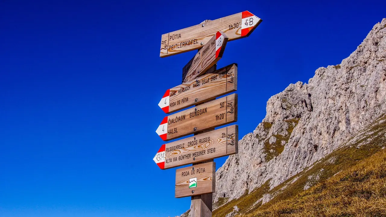 Adventurer on a secured via ferrata route in the Italian Dolomites with dramatic vertical terrain Climber ascending iron rungs on a via ferrata route with red limestone cliffs and green meadows below