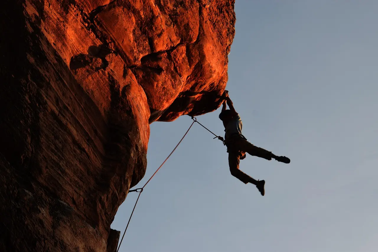 Sport climber ascending a steep limestone route in Kalymnos — a benchmark adventure and outdoor destination celebrated for route quality, accessibility, and climbing community ethos Climber mid-move on steep limestone face with ocean visible below, wearing helmet and harness