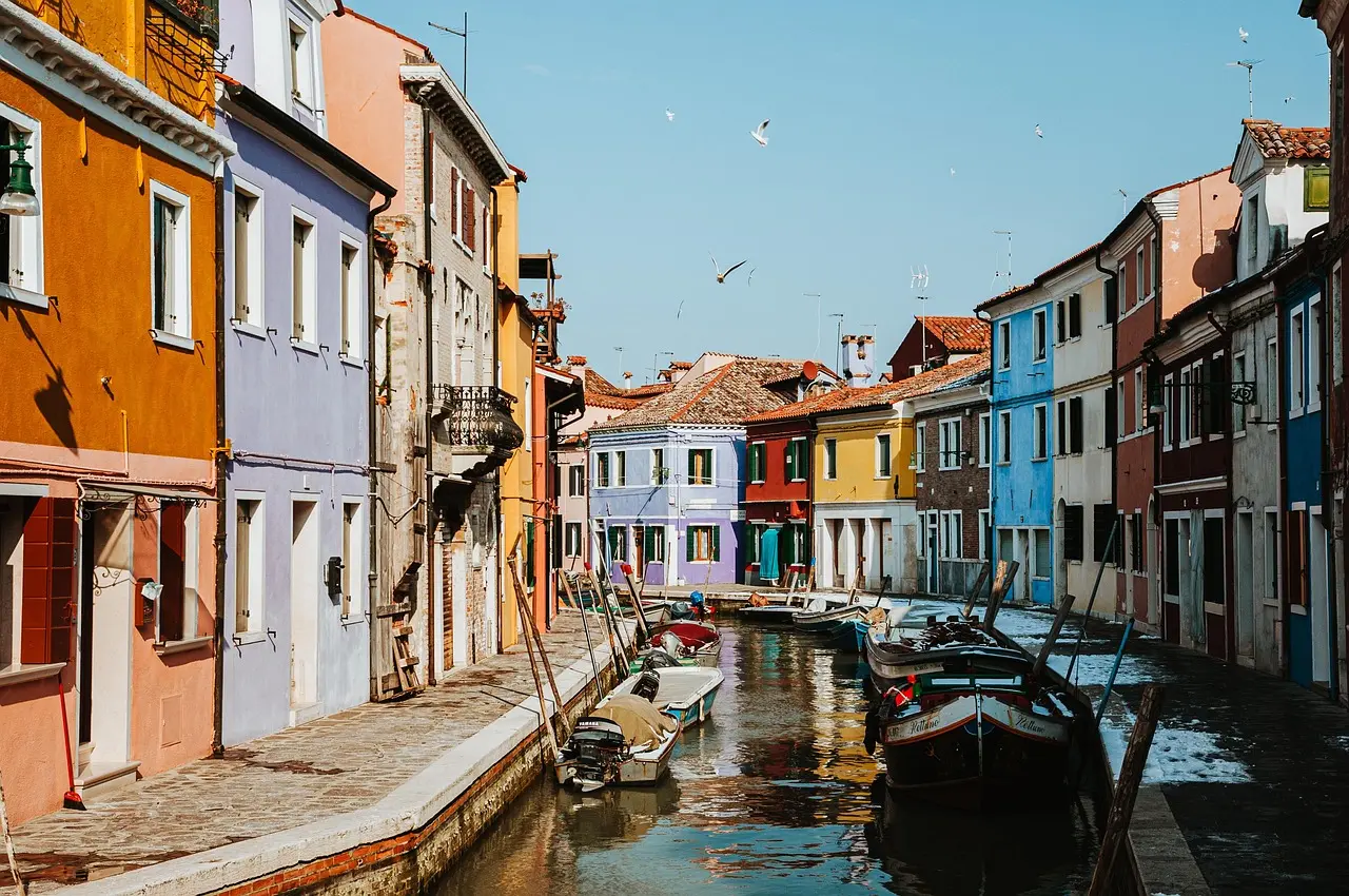 Una góndola tradicional navega por los pintorescos canales de Venecia, uno de los lugares más emblemáticos que ver en Italia. Góndola navegando por canal veneciano