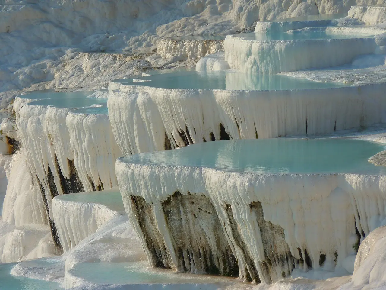 Terrazas blancas de travertino en Pamukkale con agua cristalina reflejando el cielo