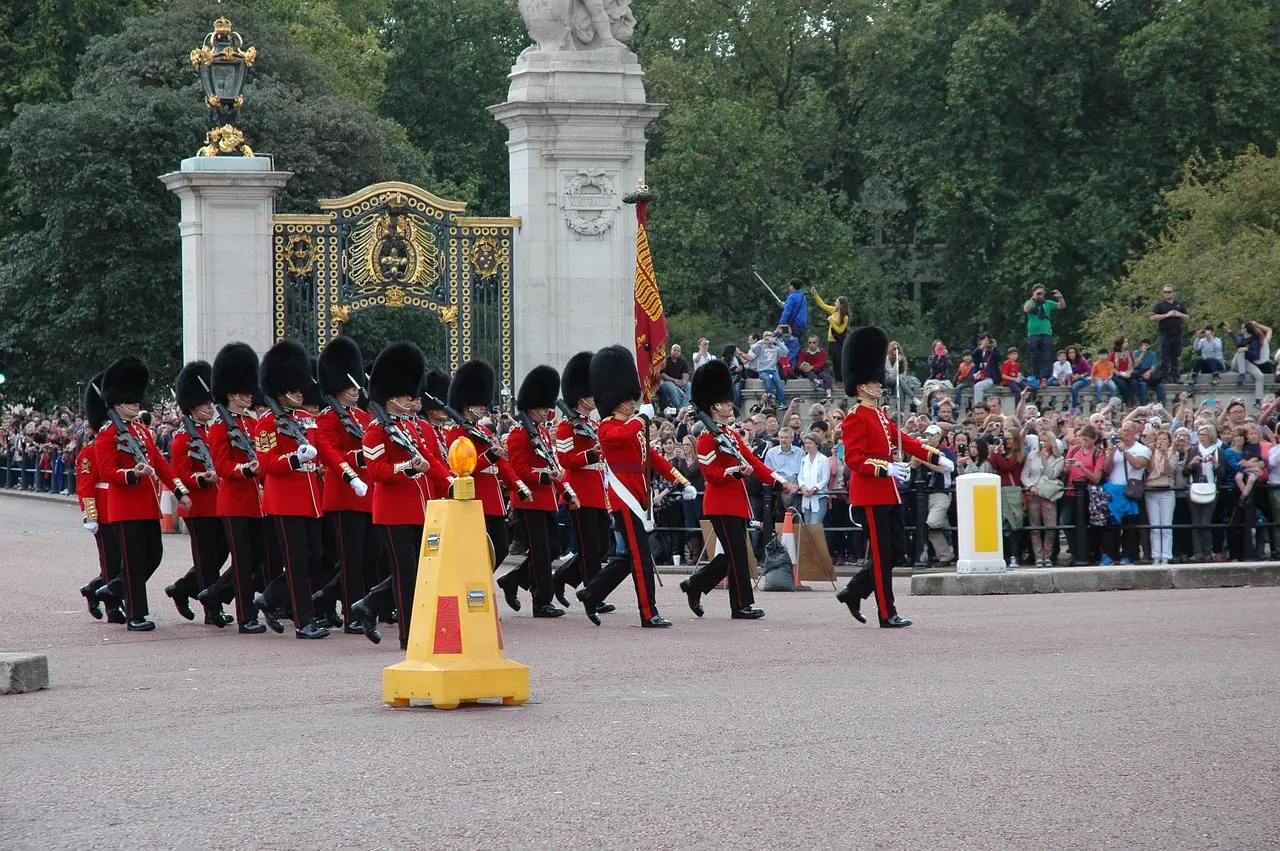 Guardias reales británicos con uniformes rojos y sombreros negros frente al Palacio de Buckingham