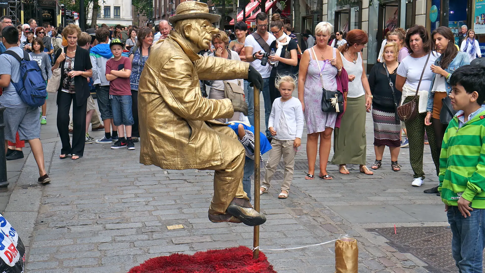 Persona disfrazada como estatua humana en Covent Garden rodeada de turistas